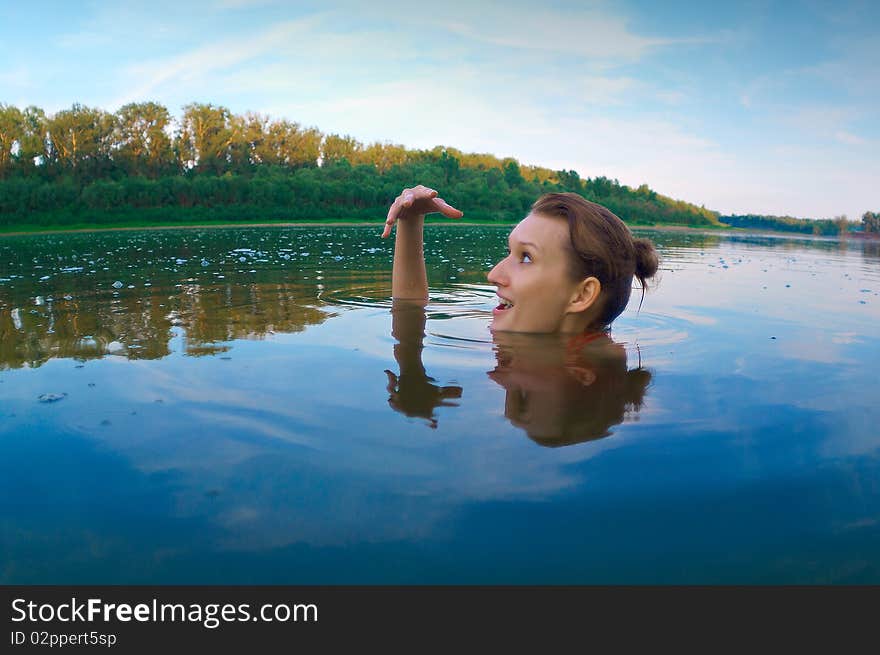 Beautiful young girl with a bright emotions swimming in the river