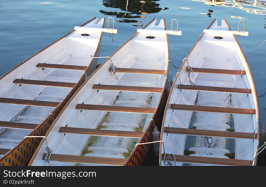 Three paddle boats in a row at a dock