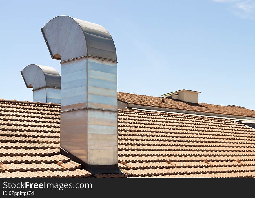 Red tiled roof with chimney on blue sky