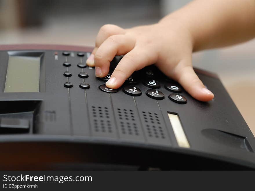 A boy hand is on the pone keyboard, he is dialing the phone number for making a call.