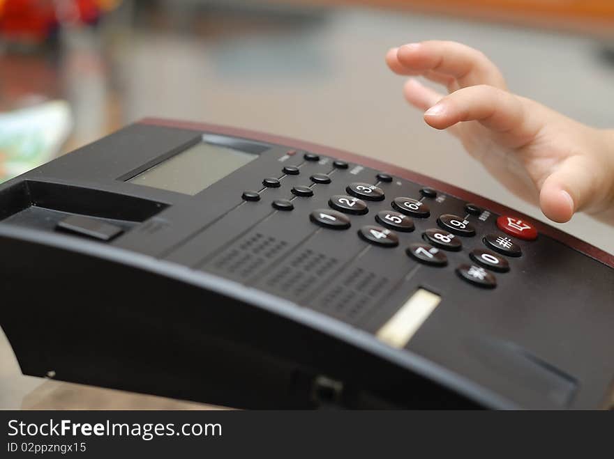 A boy hand is on the pone keyboard, he is dialing the phone number for making a call.