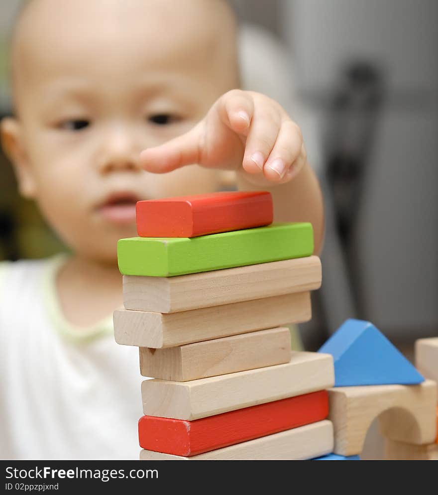 A child is playing with wooden toy blocks in home.