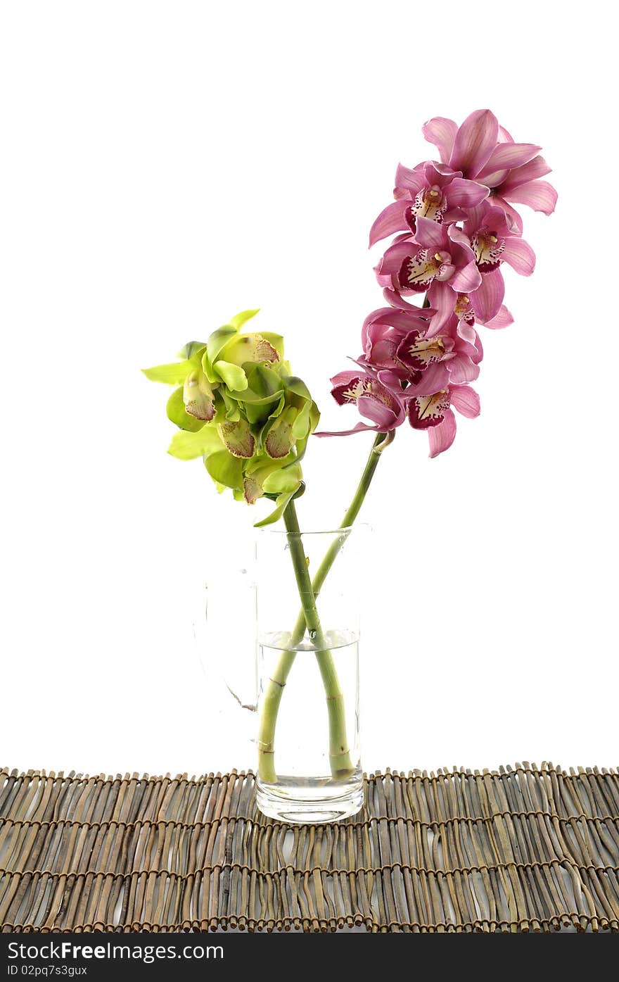 Color orchids in vase on bamboo mat