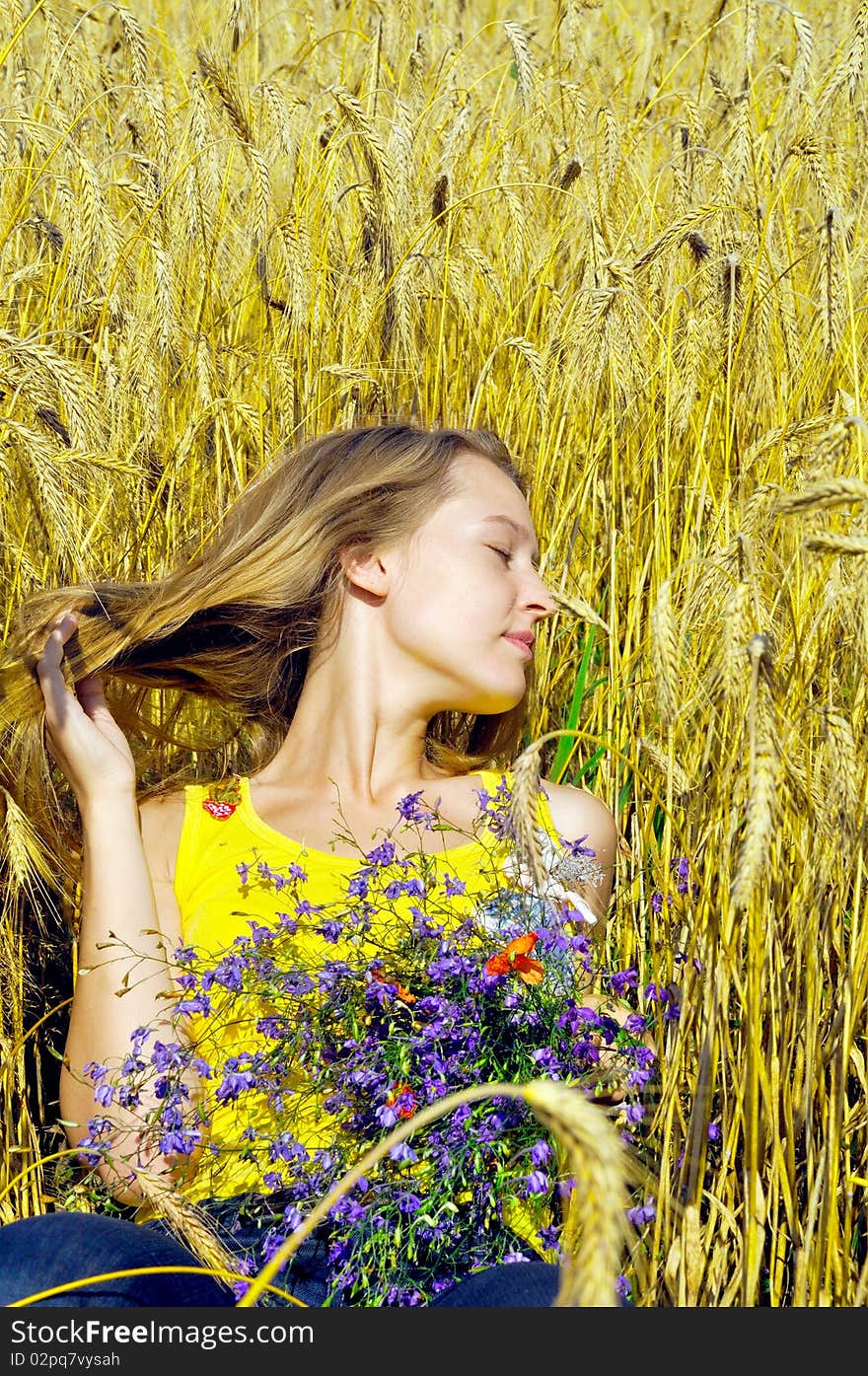 Beautiful blond girl takes sunbathe in golden field. Beautiful blond girl takes sunbathe in golden field