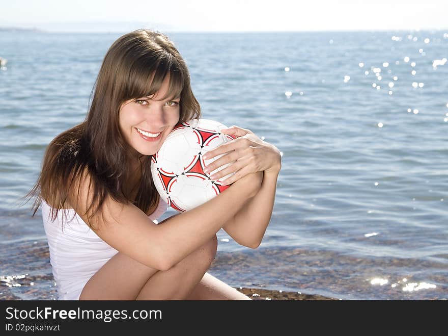 Beautiful young smiling girl in white with a ball on sunny beach. Beautiful young smiling girl in white with a ball on sunny beach