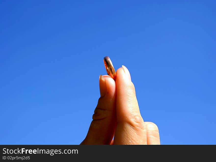 Female gold ring in a hand against the sky