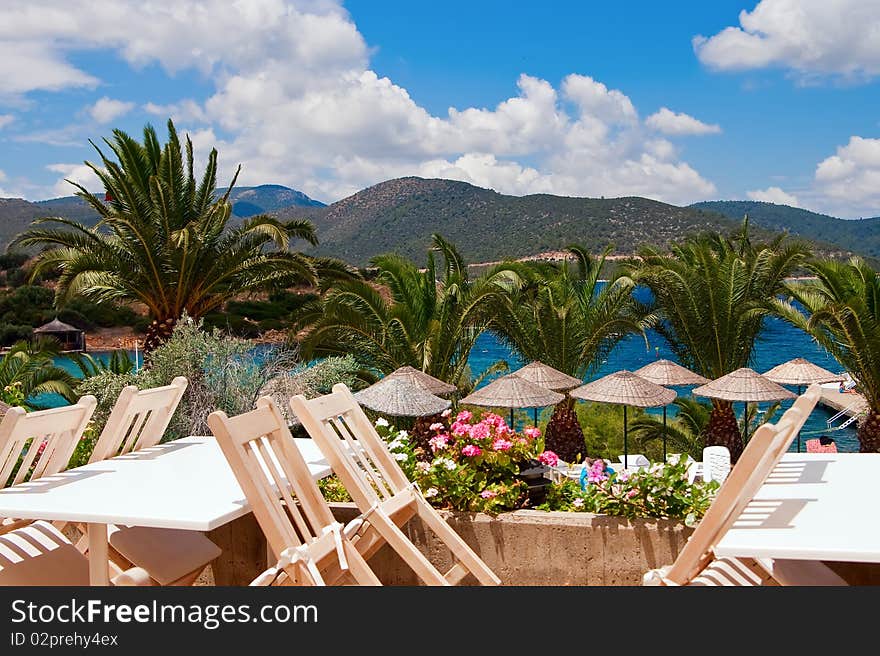 Beautiful view of a restaurant near the sea, with palms and mountains