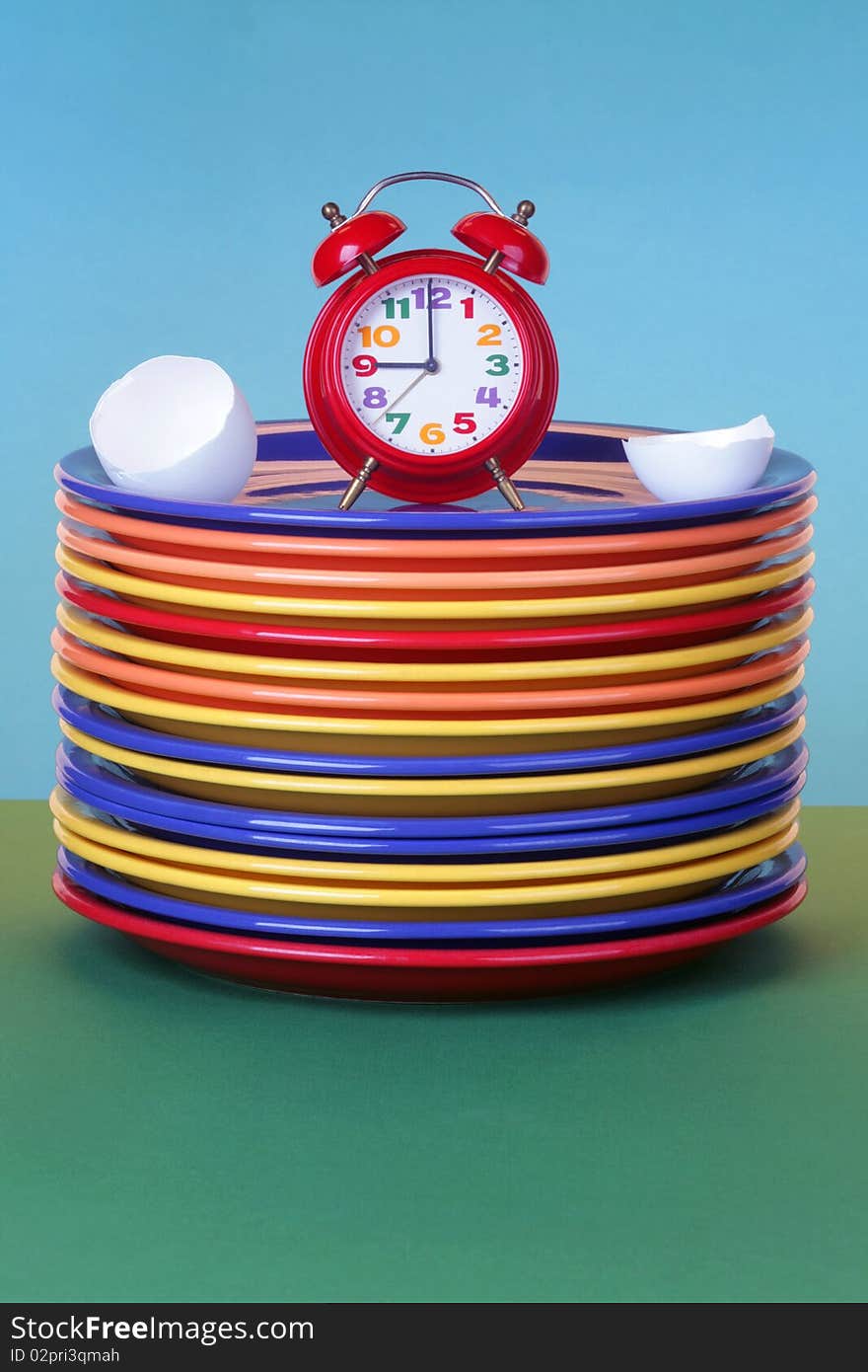 Red alarm clock and egg shell on a plate