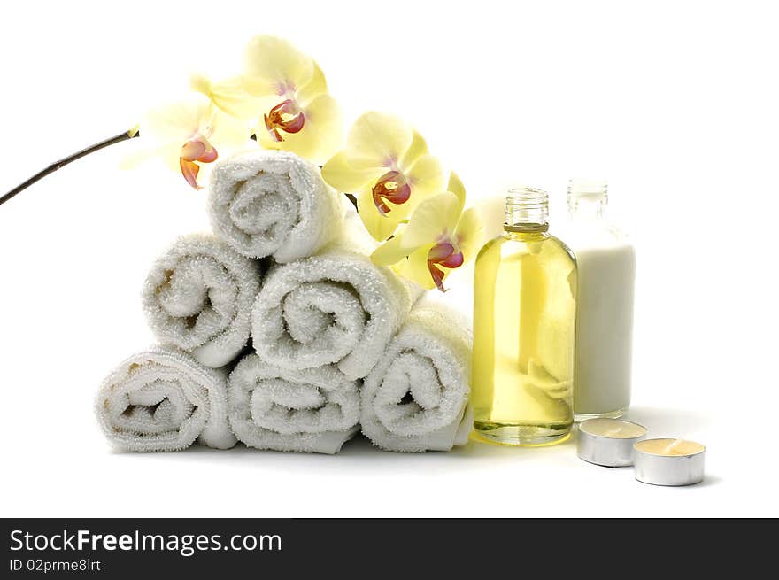 Rolled up white towel, candle, lotion with orchid. Rolled up white towel, candle, lotion with orchid