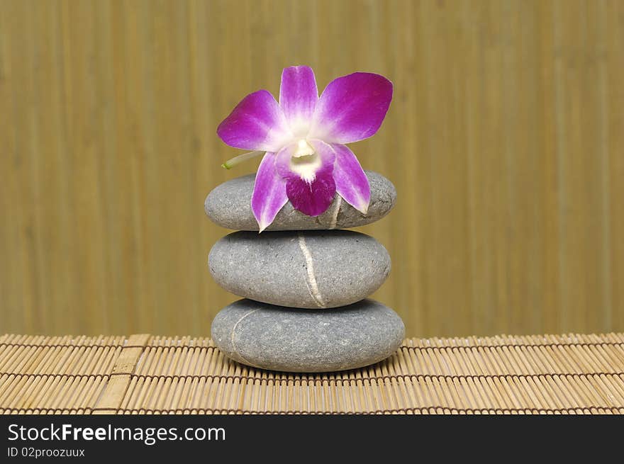 Pink orchid and stones on bamboo mat. Pink orchid and stones on bamboo mat