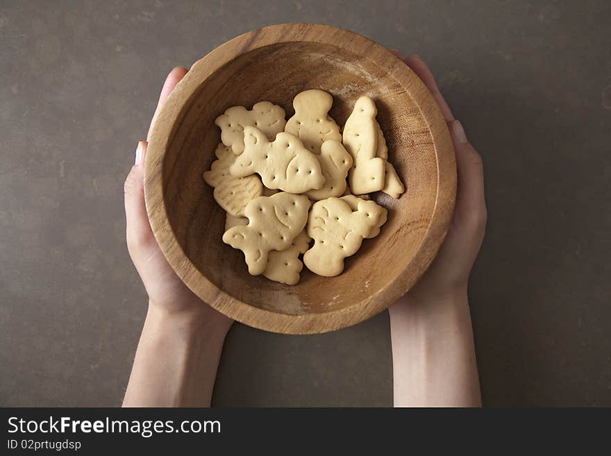 Hands holding fresh biscuit cookies in a wooden plate. Hands holding fresh biscuit cookies in a wooden plate