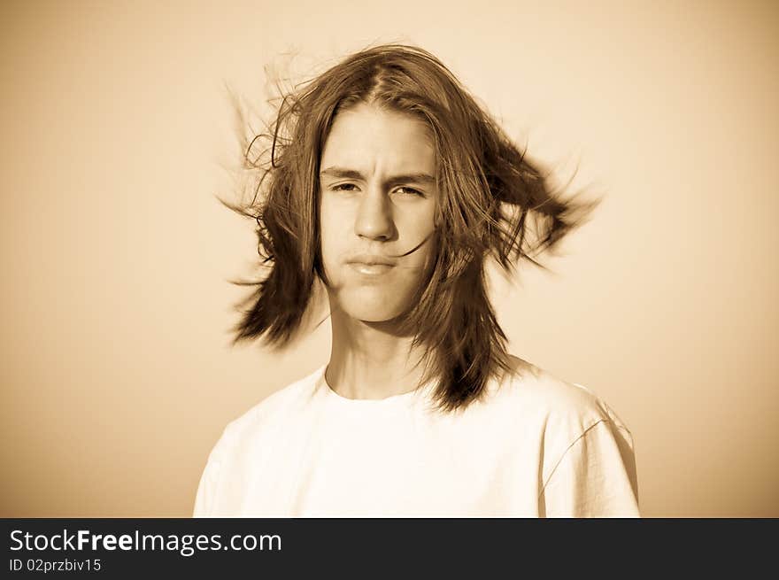 Monochrome portrait of a teenager with disheveled hair, the wind against the sky