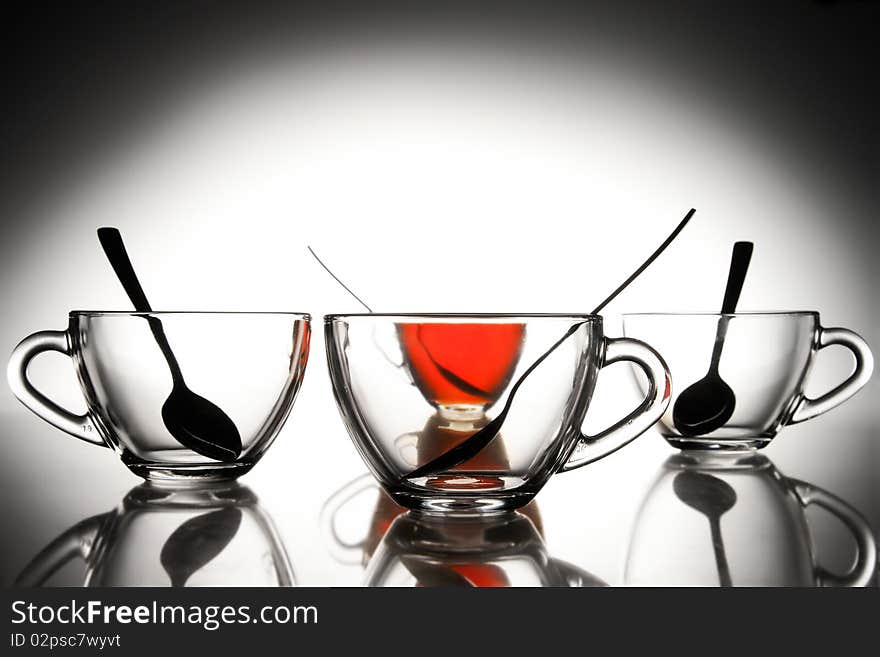 4 glass tea cups with reflection on white and one with tea at 10Mps. 4 glass tea cups with reflection on white and one with tea at 10Mps