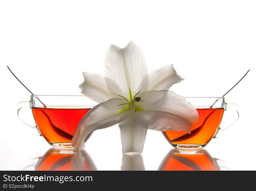 2 glass tea cups and flower with reflection on white at 10Mps. 2 glass tea cups and flower with reflection on white at 10Mps