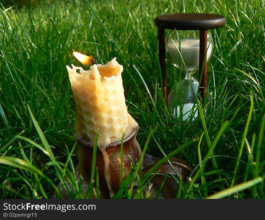 Time is burning scene with sandglass and candle. Time is burning scene with sandglass and candle