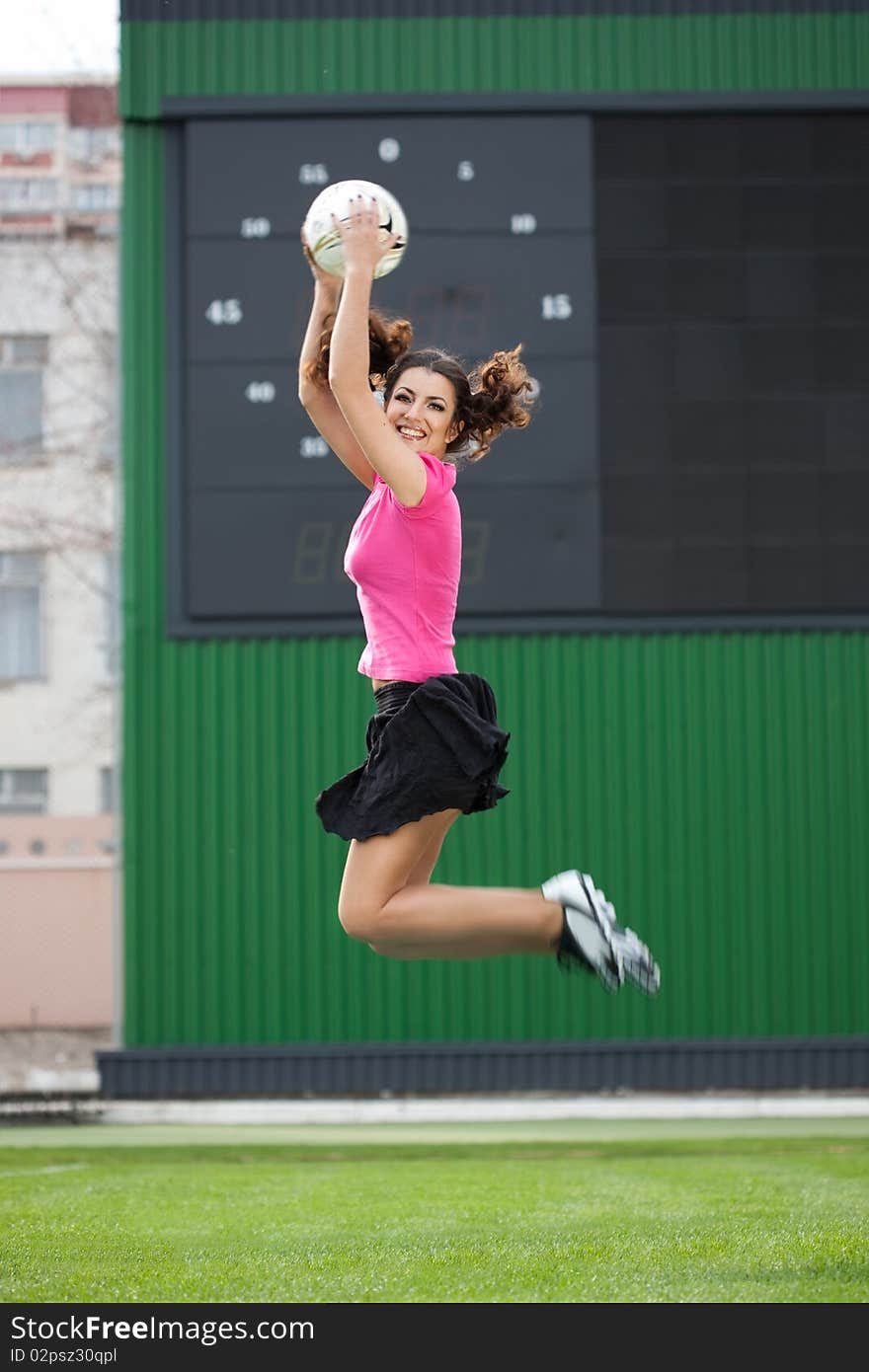 Girl cheerleaders jumping with a soccer ball