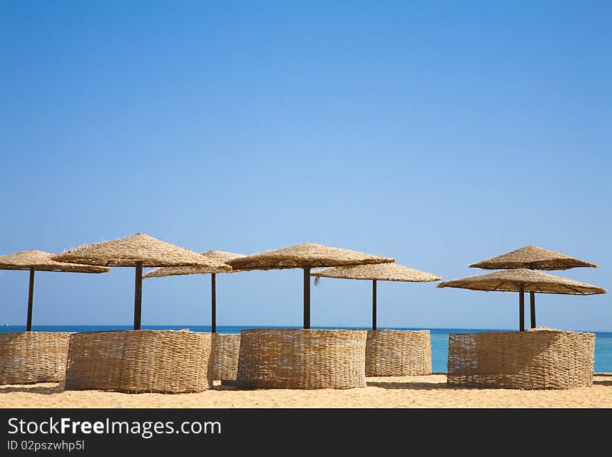 Palm beach umbrellas on a tropical island summer resort. Generic tropical beach