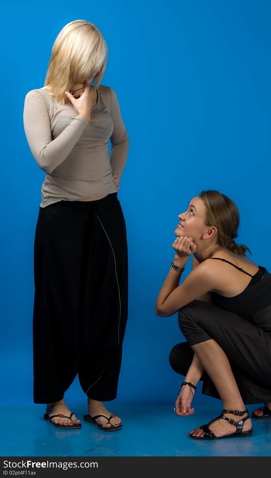 Two beautiful smiling friends girls isolated on blue background. Two beautiful smiling friends girls isolated on blue background.