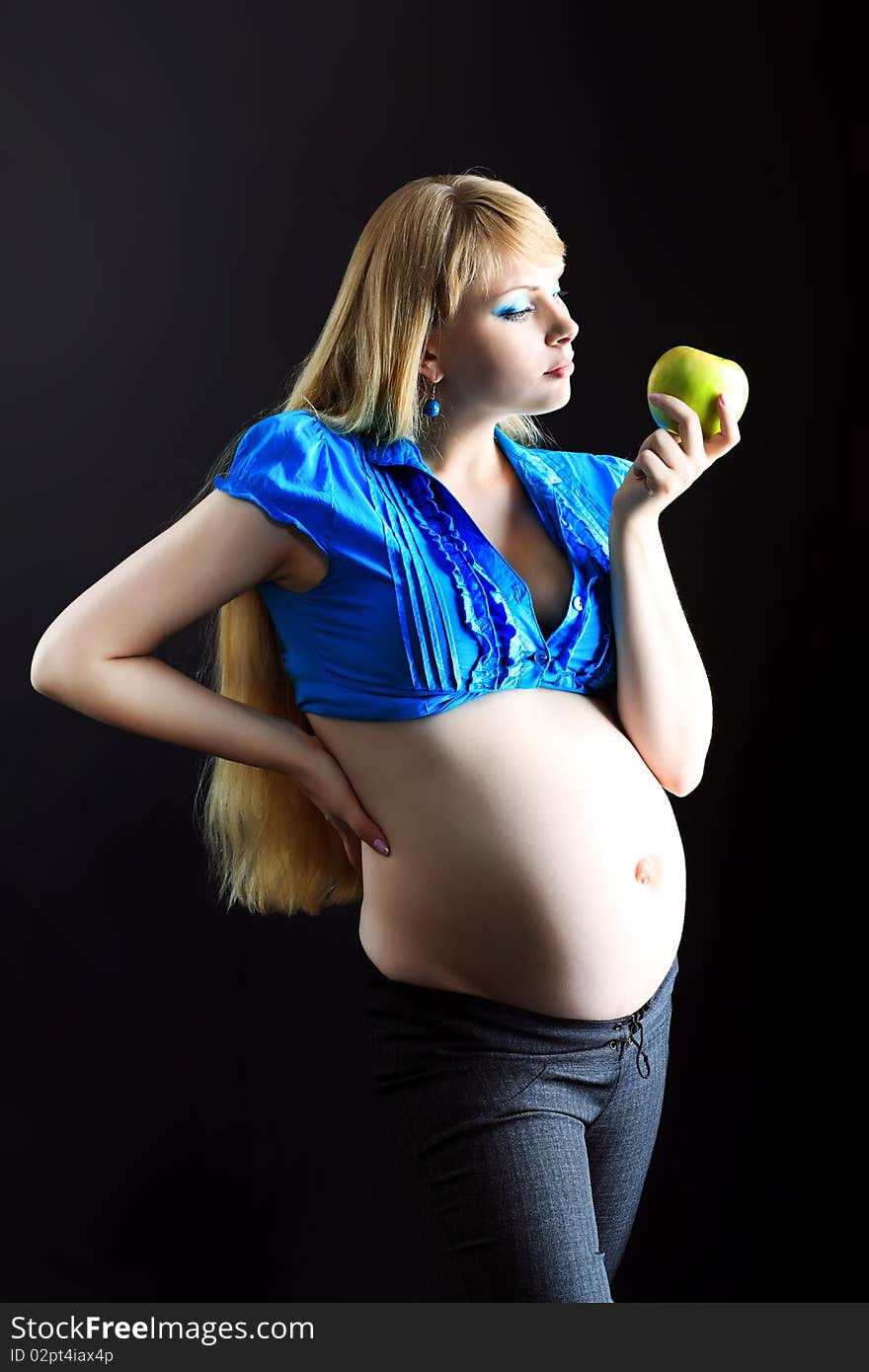 Portrait of a beautiful pregnant woman eating fresh apple. Over black background. Portrait of a beautiful pregnant woman eating fresh apple. Over black background.