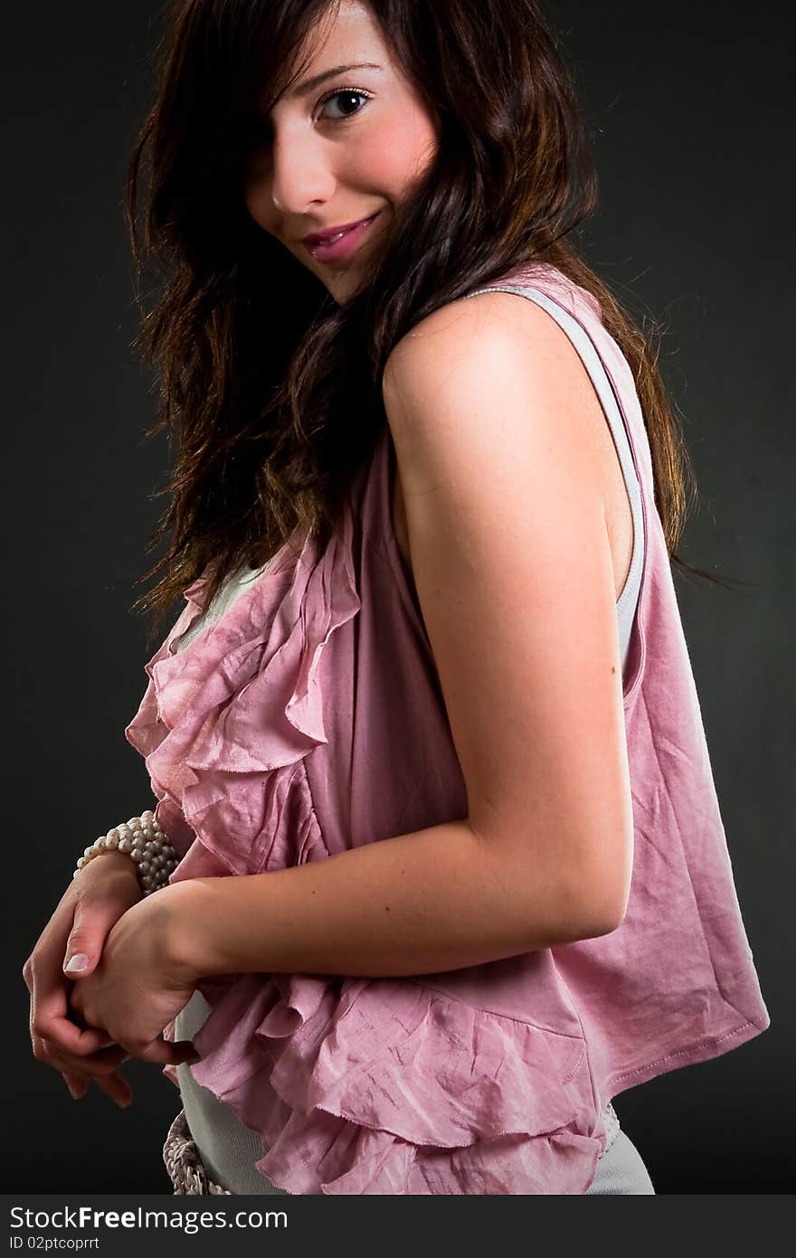 Beautiful teen girl in pink clothes over dark background