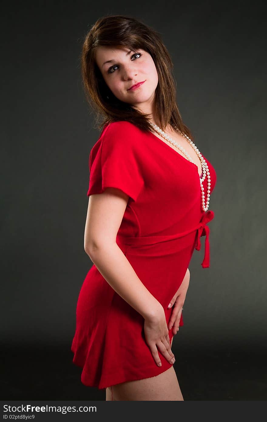 Beautiful teen girl in red dress over dark background