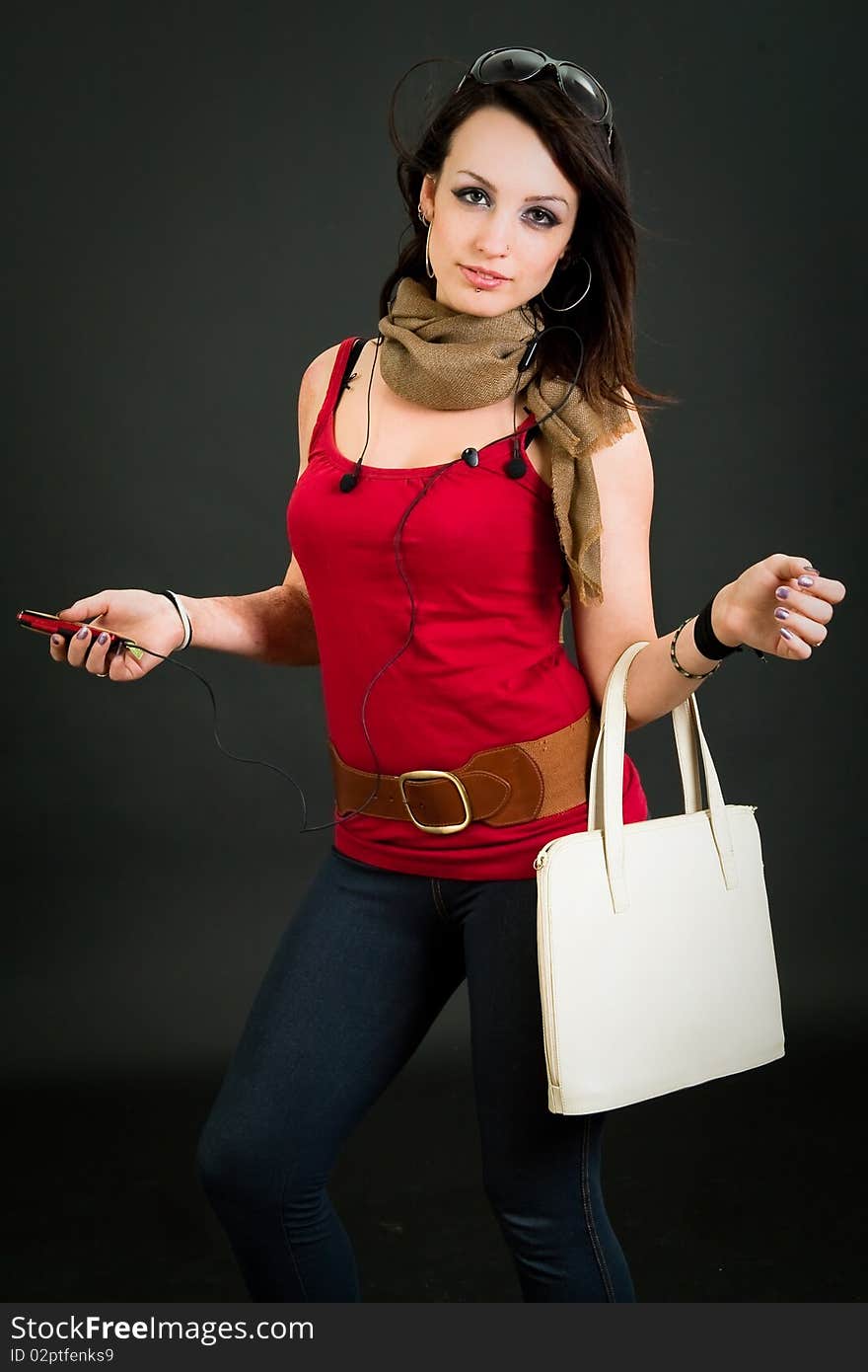 Beautiful teen girl with bag and mp3 player over dark background