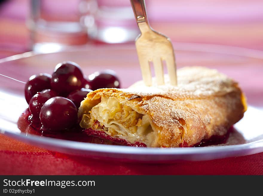 Apple strudel with hot cherries on a plate