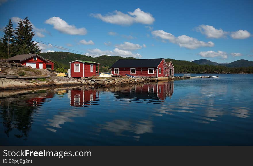 Beautiful nordic red shiphouses, boats and cloud reflections in a water. Shot in sunny beautifull day. Beautiful nordic red shiphouses, boats and cloud reflections in a water. Shot in sunny beautifull day.