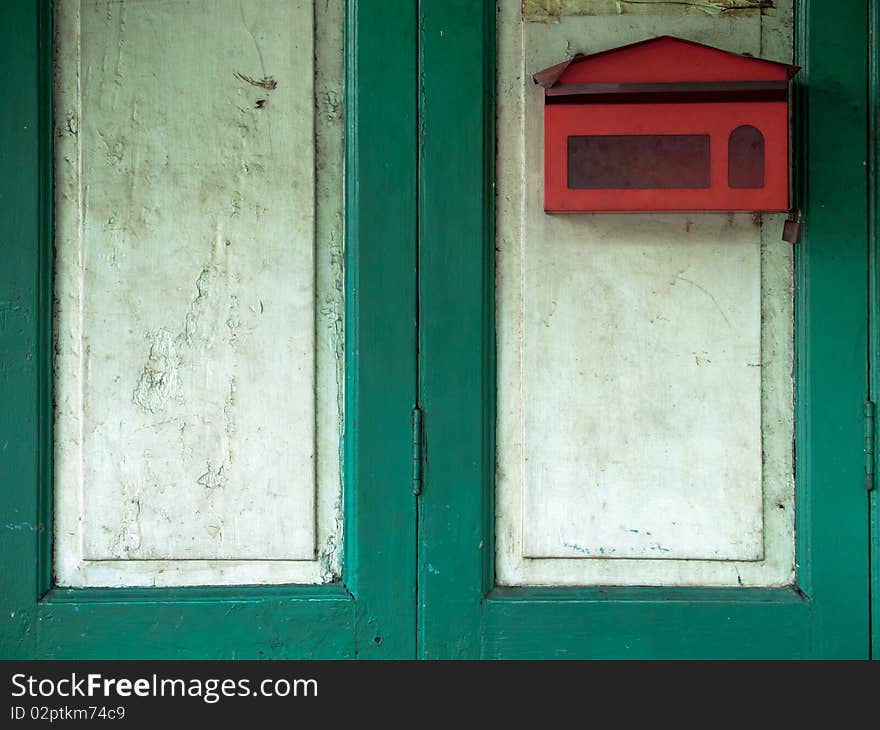 Red mail box on green wood door