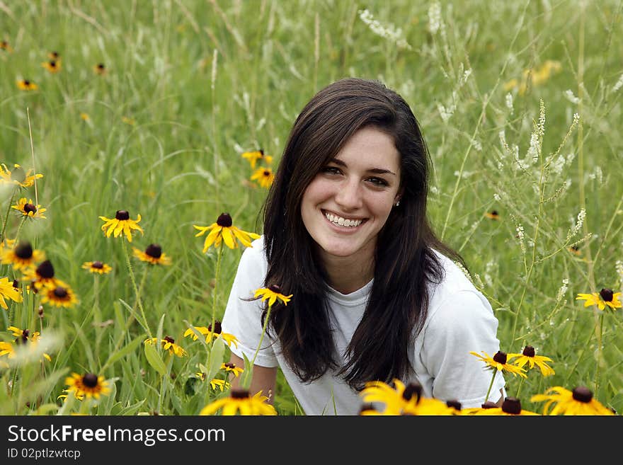 Young smiling woman in green meadow with yellow coneflowers. Young smiling woman in green meadow with yellow coneflowers