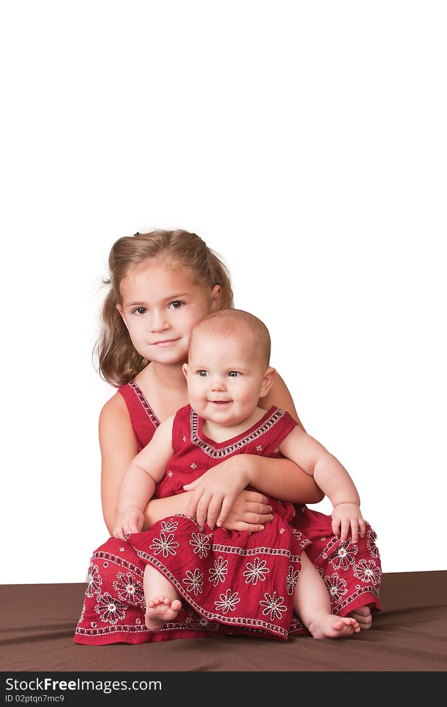 Pretty 5 year old holding little sister and both wearing matching dresses. Pretty 5 year old holding little sister and both wearing matching dresses.