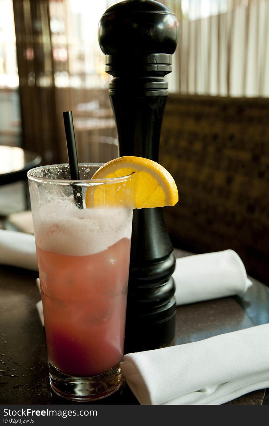 Drinking glass with pink soda and slice of orange