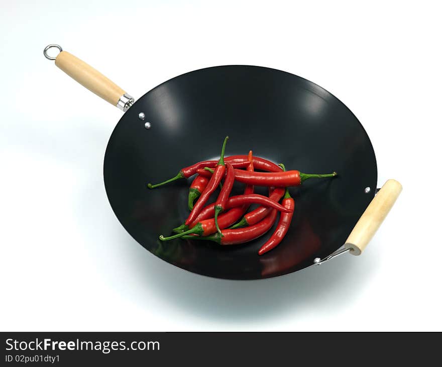 Red chilli peppers in a wok isolated against a white background