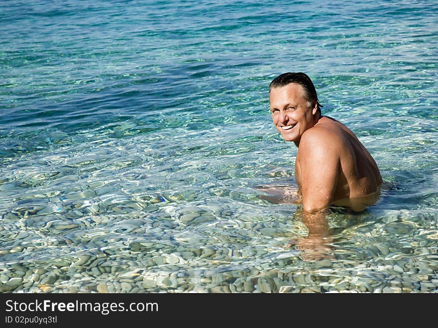 A color portrait photo of a happy smiling man in his forties relaxing in the beautiful blue sea. A color portrait photo of a happy smiling man in his forties relaxing in the beautiful blue sea.