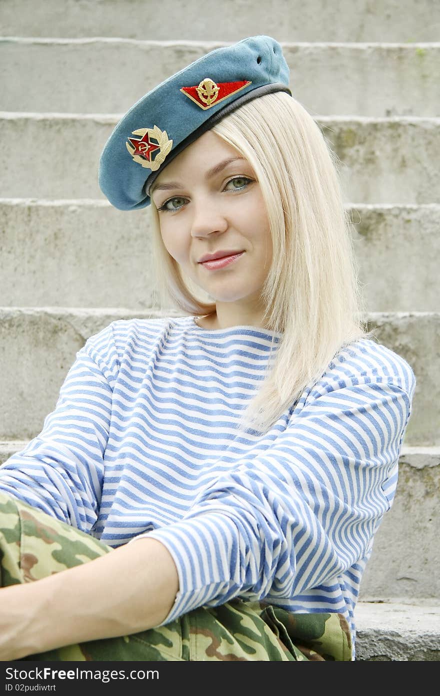 The woman with green eyes in the military form sits on a ladder. The woman with green eyes in the military form sits on a ladder