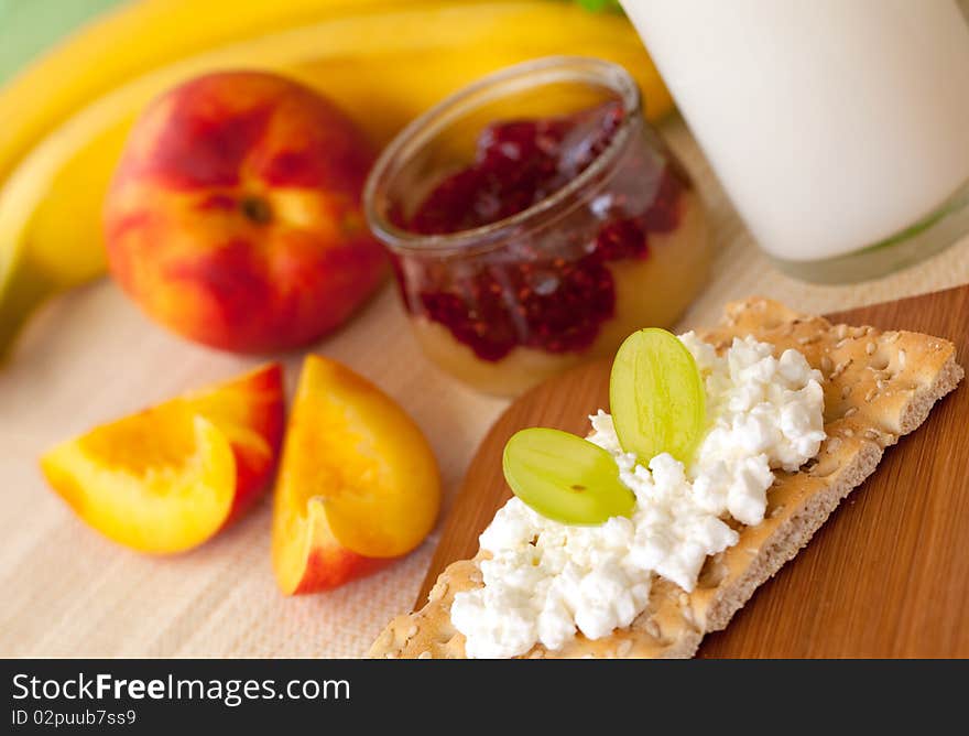 Breakfast with fruits and jam on a table and crispbread in front.