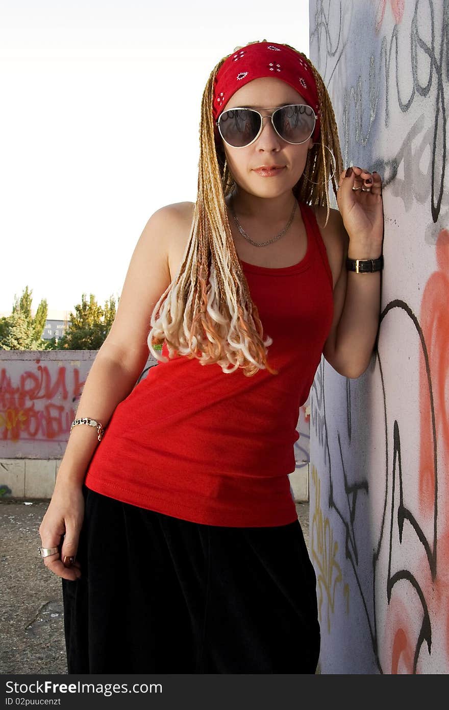 Teenage rapper girl standing outdoors at graffiti sprayed wall. Teenage rapper girl standing outdoors at graffiti sprayed wall