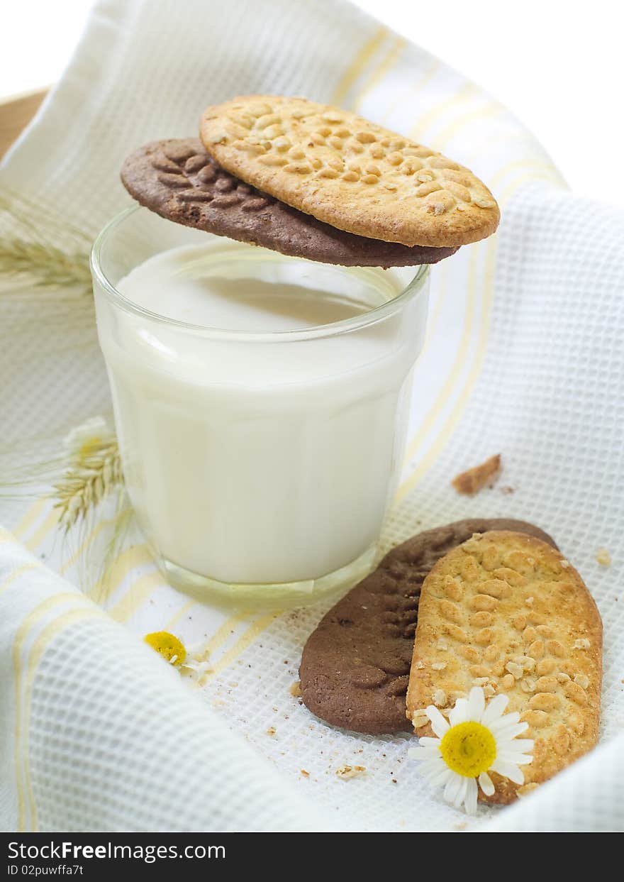 Glass of milk and cookies on light kitchen towel