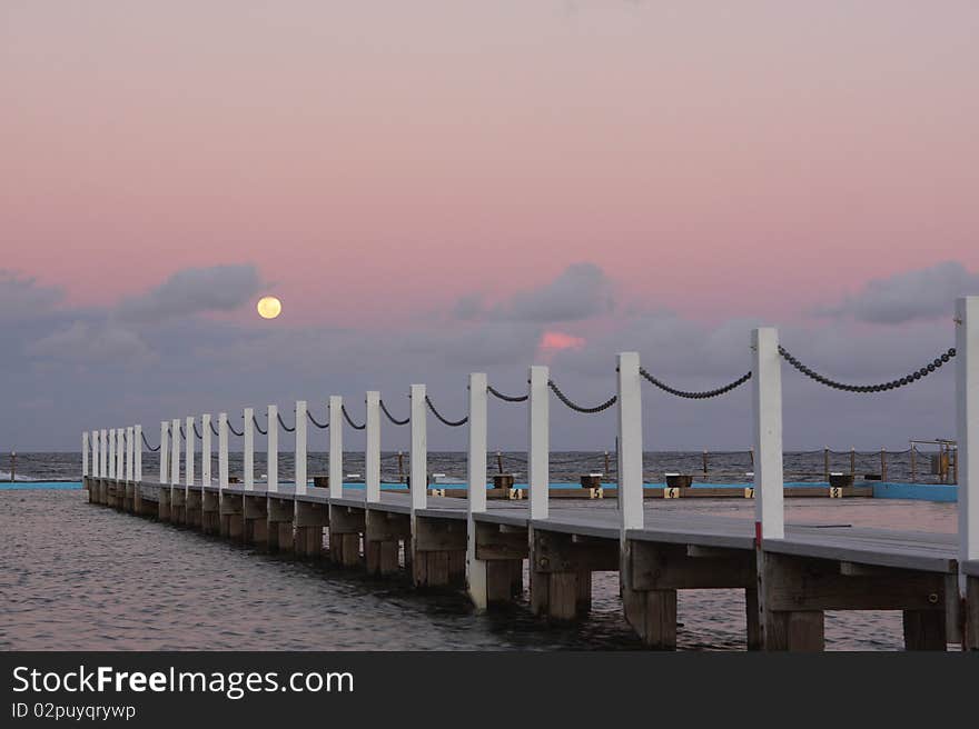 Full moon rising over the ocean at sunset