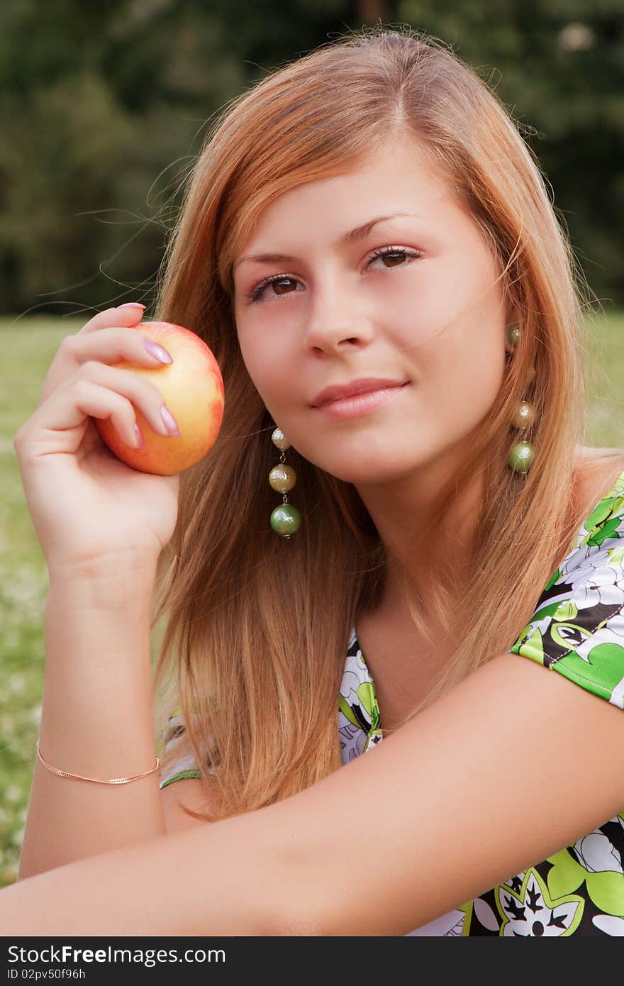 Young beautiful girl relaxing on the field with an apple in his hand. Young beautiful girl relaxing on the field with an apple in his hand