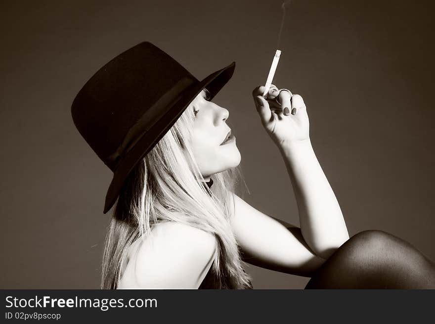 Beautiful blonde woman with hat smoking a cigarette. Fashion art photo. Beautiful blonde woman with hat smoking a cigarette. Fashion art photo