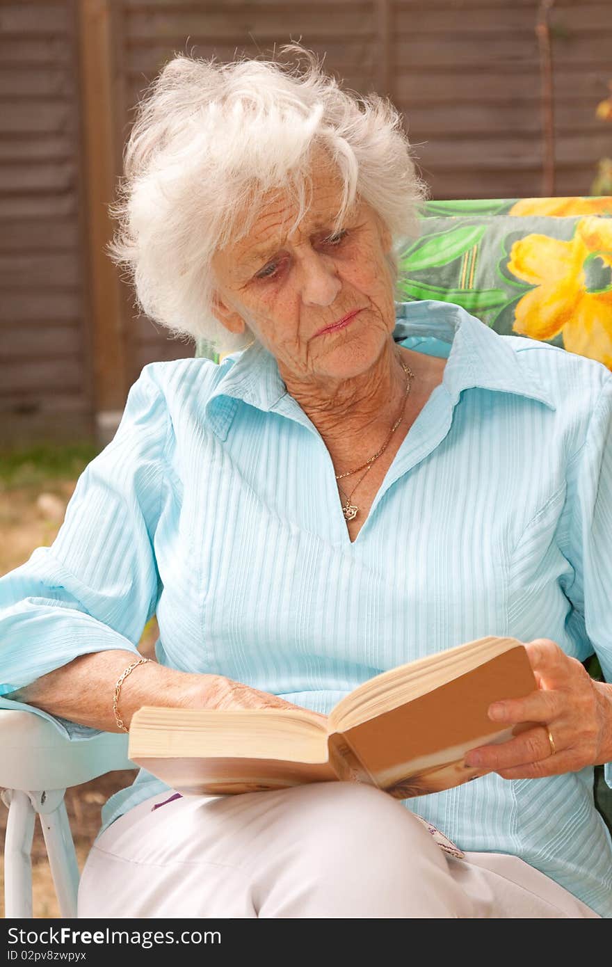 Mature woman relaxing with a book in her garden. Mature woman relaxing with a book in her garden