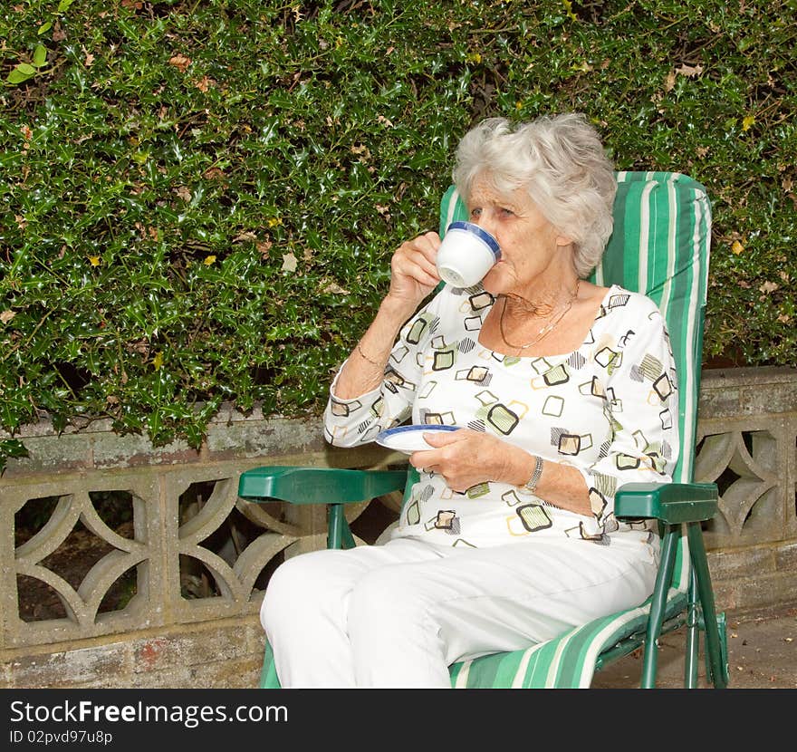 Senior lady enjoying a cup of tea in the garden. Senior lady enjoying a cup of tea in the garden