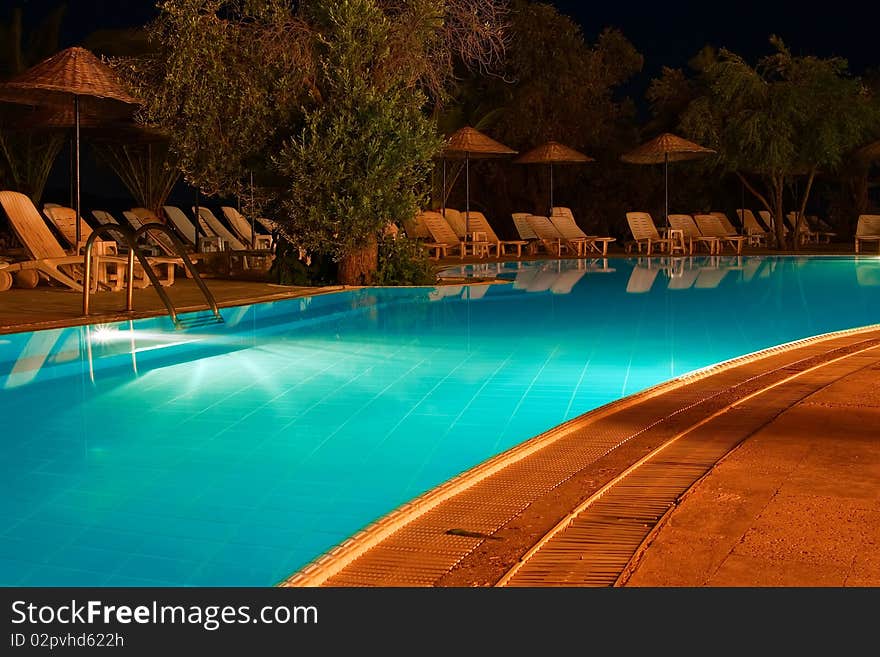 Nightshot of a swimming pool and sun chairs. Nightshot of a swimming pool and sun chairs