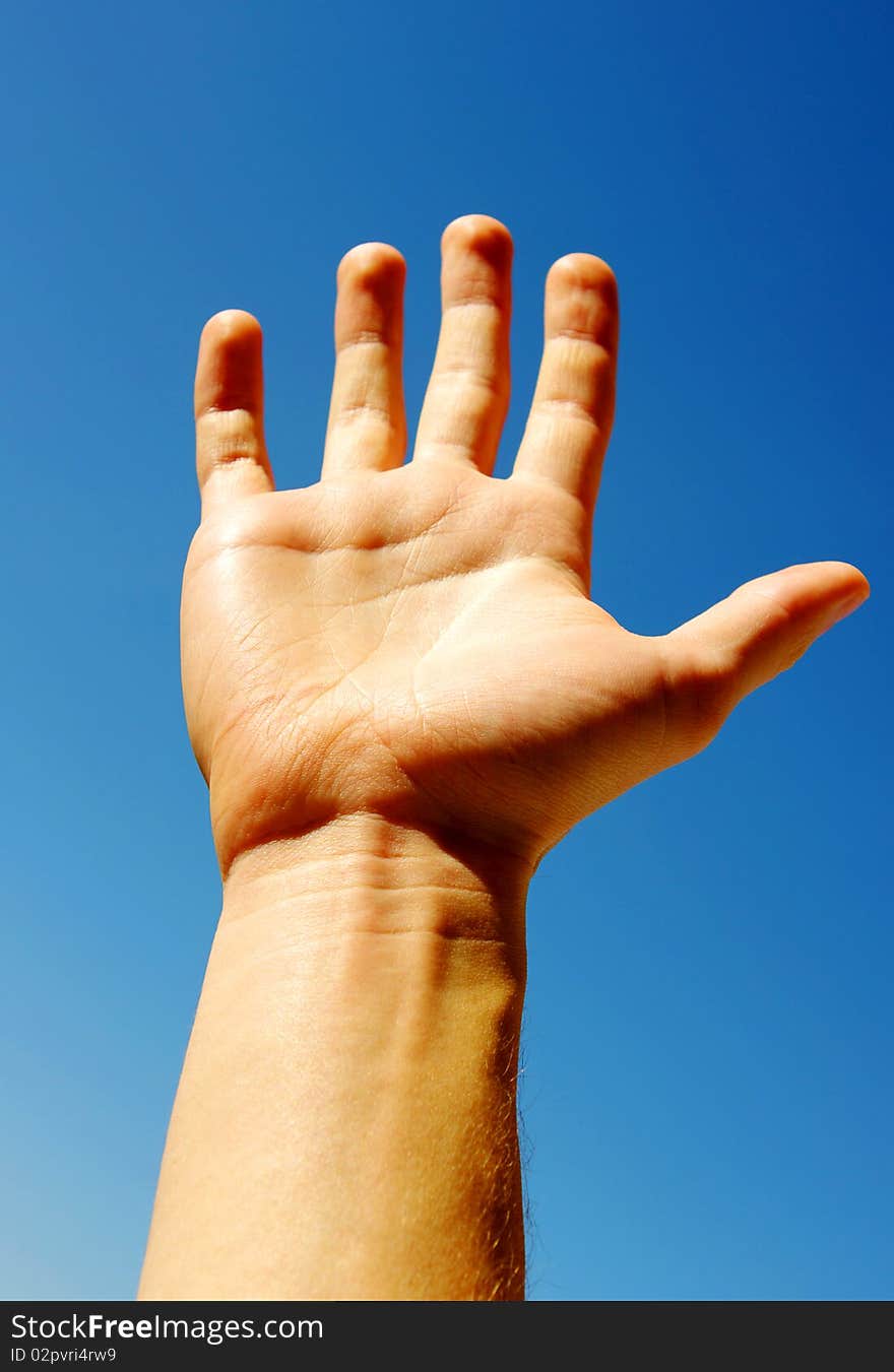 A hand begging alms on a sky background