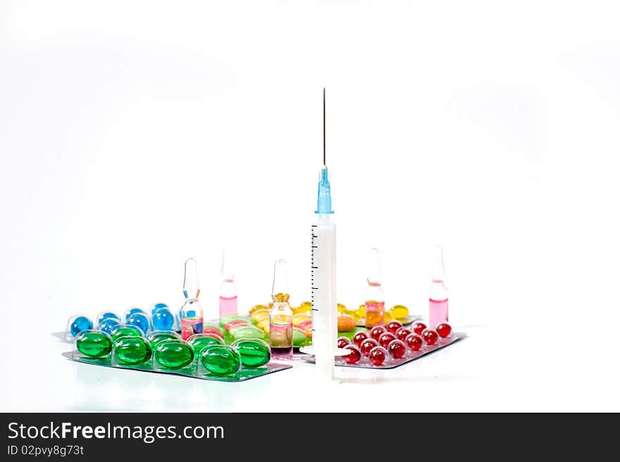 Various pills and syringe on white background