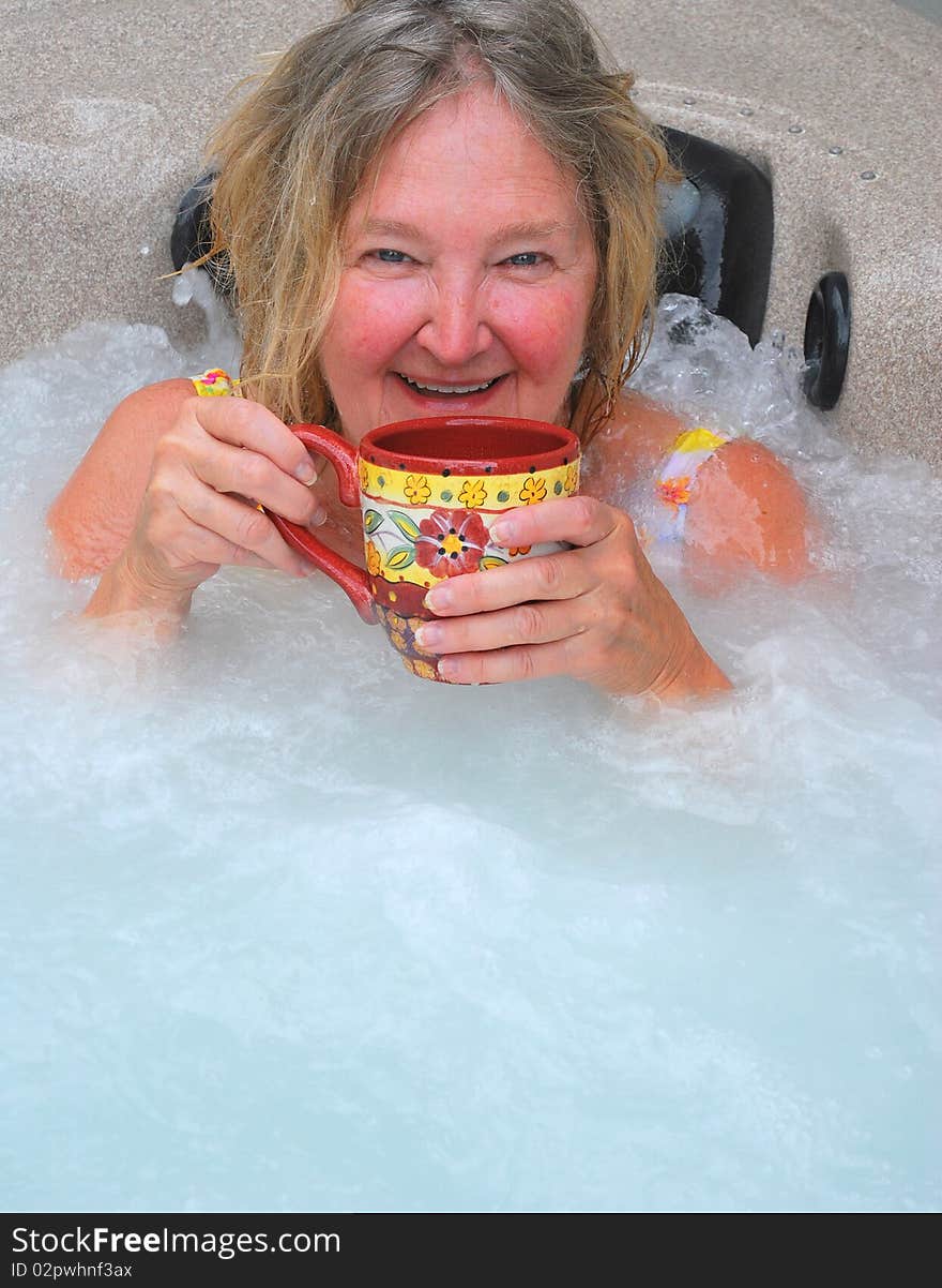 Woman having her morning coffee while relaxing in the hot tub. Woman having her morning coffee while relaxing in the hot tub.