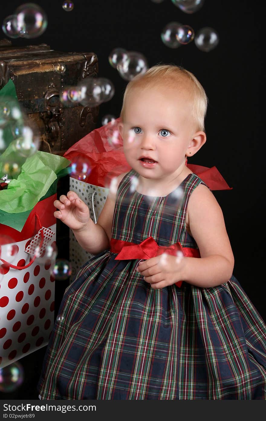 Cute blond toddler infront of an antique trunk with christmas presents. Cute blond toddler infront of an antique trunk with christmas presents