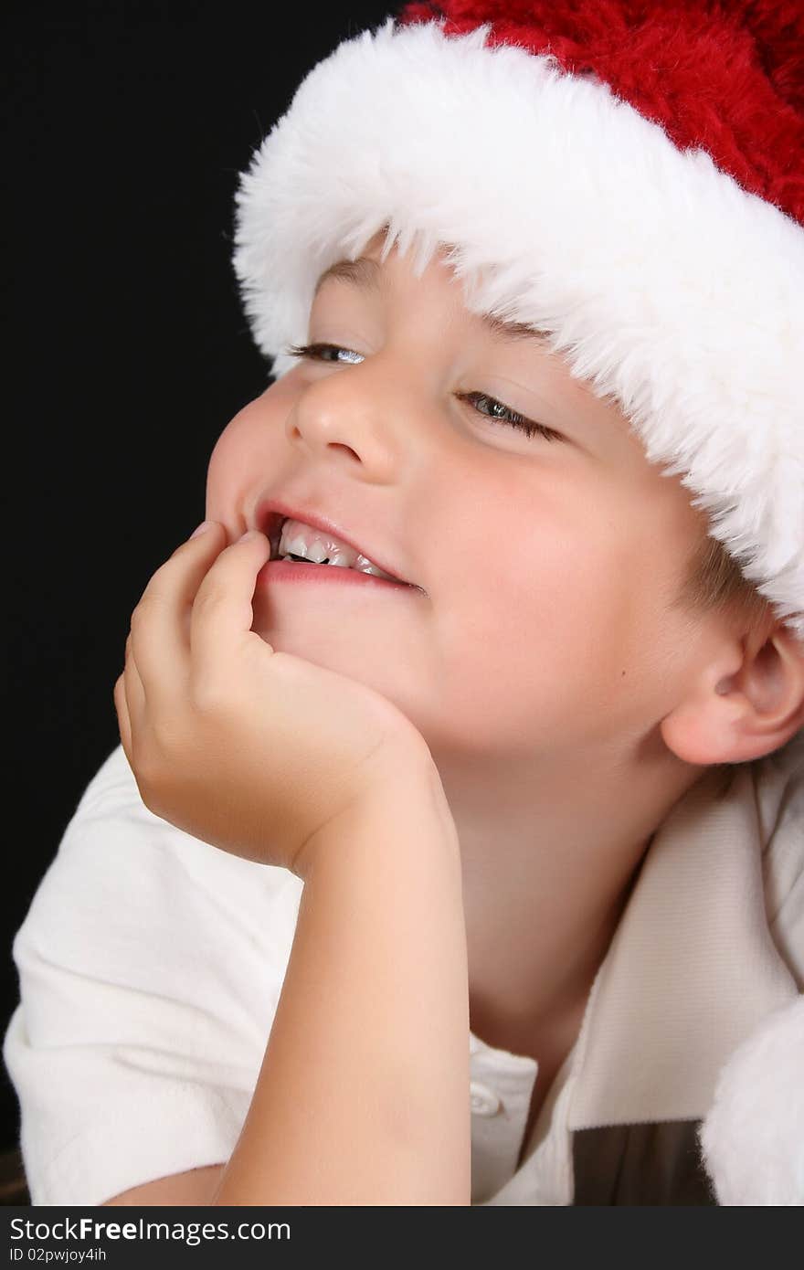 Cute young boy wearing a christmas hat against a black background. Cute young boy wearing a christmas hat against a black background