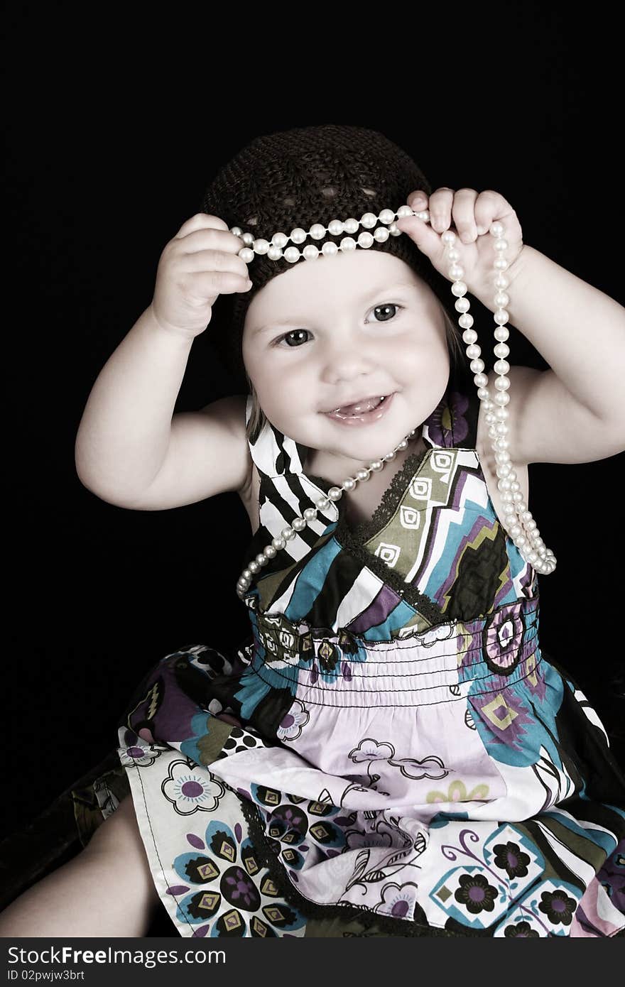 Beautiful little blond girl playing with a string of pearls